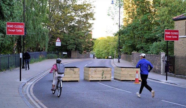 Three wooden planters placed across the carrigeway to block motor vehicles but allow walkers and cyclists free passage